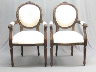 A pair of 20th Century Victorian style mahogany open arm salon chairs upholstered in Kaliko, raised on turned and fluted supports