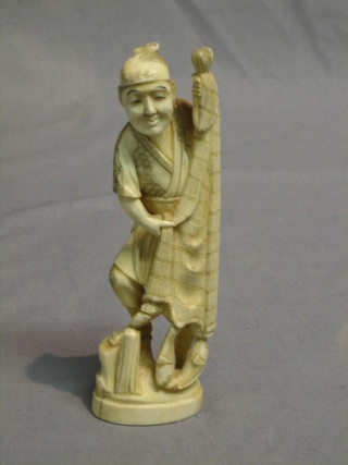 A carved ivory figure of a standing fisherman with net and fish 6"
