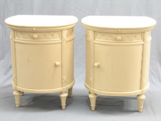 A pair of cream painted Continental demi-lune bedside cabinets fitted a brushing slide and drawer, each with a cupboard enclosed by a panelled door, raised on turned supports 22"