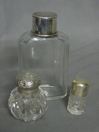 A cut glass flask with silver plated folding cup, a cut glass salts bottle with silver lid, a cut glass dressing table with silver lid (f)