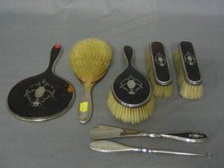 A 7 piece silver and tortoiseshell backed dressing table set comprising pair of hair brushes (1f), pair of clothes brushes, hand mirror, button hook and shoe horn, Birmingham 1924 and 1925