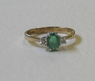 A lady's gold dress ring set an emerald supported by 2 diamonds