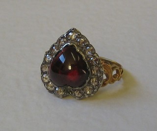 A lady's 18ct yellow gold dress ring set a heart shaped cabouchon cut garnet surrounded by diamonds