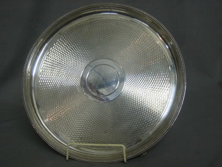 A circular silver plated salver with bead work border, raised on bracket feet 12"