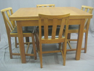 A 1930's honey oak dining suite comprising drawleaf dining table and 4 stick and bar back dining chairs by Heales 