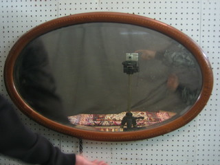 An Edwardian oval bevelled plate mirror contained in an inlaid mahogany frame 30"