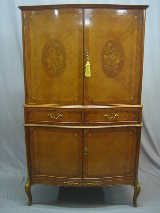 A 20th Century French Kingwood cocktail cabinet, the upper section with moulded cornice enclosed by an inlaid door, the base fitted 2 drawers above a double cupboard, raised on cabriole supports 35"