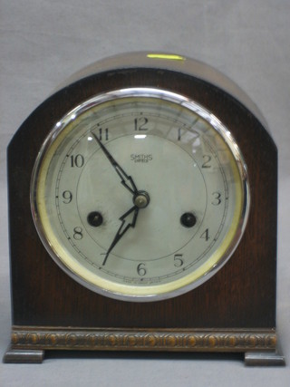 A 1930's 8 day striking mantel clock with silvered dial and Arabic numerals contained in an arch shaped oak case by Smith Enfield