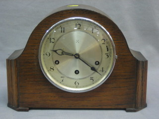 A 1930's chiming mantel clock with silvered dial and Arabic numerals contained in an oak arch shaped case