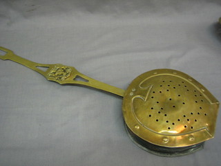 A brass chestnut roaster with pierced lid and armorial decoration