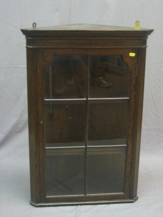 A 19th Century oak hanging corner cabinet with moulded cornice, the interior fitted shelves, enclosed by astragal glazed panelled door 20"