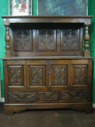 A Victorian oak court cupboard, constructed from old timber, the raised top with panelled back, the base fitted a cupboard enclosed by panelled doors above 3 long drawers, raised on bracket feet 57"
