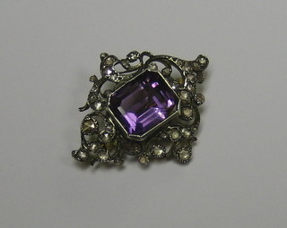 A lady's gold brooch set a lozenge cut amethyst supported by numerous diamonds