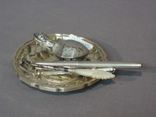 An embossed white metal ashtray decorated a coin 3 1/2", a silver cased felt tip, a silver swizzle stick, an Eastern silver condiment in the form of a turtle and a small button hook