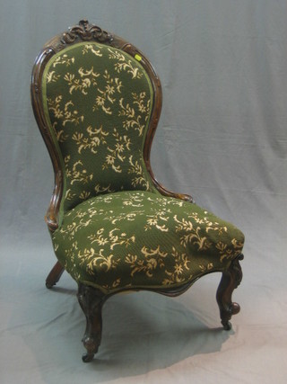A Victorian carved walnut show frame spoon back armchair upholstered in green material raised on cabriole supports