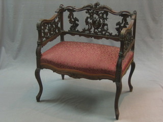 A Victorian heavily carved open arm stool with pierced fret work back and upholstered seat, raised on cabriole supports 25"