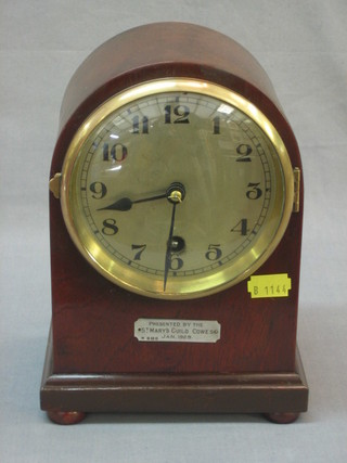 An Edwardian mantel clock with silver dial contained in an arch shaped mahogany case