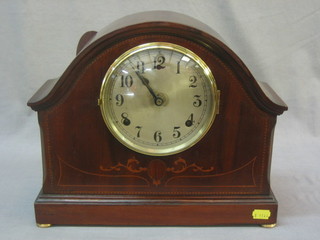 A striking mantel clock with silvered dial and Arabic numerals contained in an arch shaped inlaid mahogany case