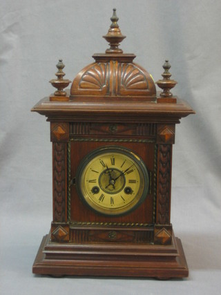 A Continental striking bracket clock with paper dial and Roman numerals contained in a carved walnut case