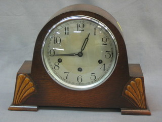A chiming mantel clock with silvered dial and Arabic numerals contained in an oak case arch shaped case