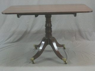 A handsome Regency rectangular breakfast table, raised on pillar and tripod supports ending in brass caps and castors 48"