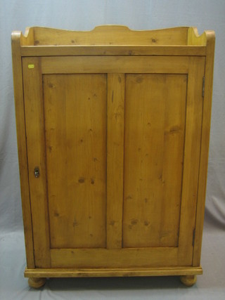 A 19th Century Continental pine cabinet with three-quarter gallery, the interior fitted shelves enclosed by a panelled door, raised on bun feet 34"