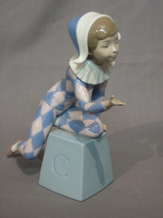 A Lladro figure of a seated harlequin on a cube (cube marked C) 8"