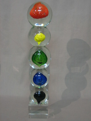 A glass sculpture in the form of 5 coloured balls raised on a square base 16"