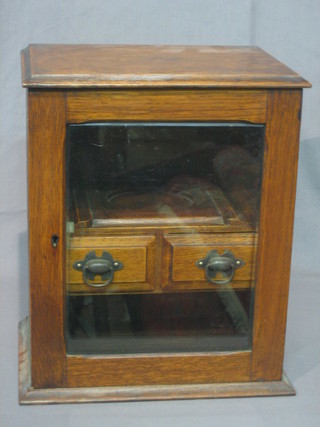 An Edwardian oak smoker's cabinet fitted a pipe rack and 2 drawers, enclosed by a glazed panelled door 10 1/2"