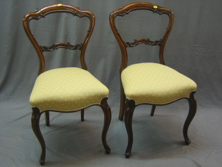 A pair of Victorian rosewood spoon back dining chairs with shaped mid rails, the seats of serpentine outline, raised on cabriole supports