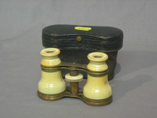 A pair of "ivory" covered opera glasses contained in a leather carrying case