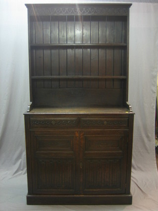 A 19th Century carved oak dresser, the raised back with moulded and carved cornice, the base fitted 2 drawers above a double cupboard, raised on a platform base 40"