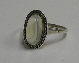 A lady's silver dress ring set a cabouchon cut moon stone in a marcasite mount