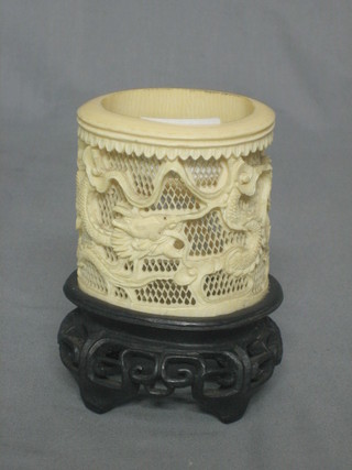 A cylindrical pierced ivory vase 3", raised on a hardwood stand
