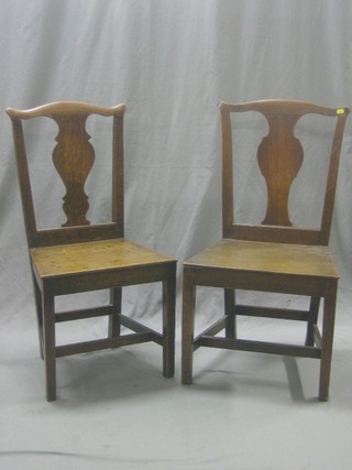 A matched pair of 18th Century Country oak Chippendale style hall chairs with solid seats, raised on square tapering supports