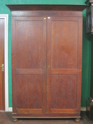 A  mahogany Channel Islands wardrobe with moulded cornice and shelves interior enclosed by panelled doors, raised on bun feet 55"