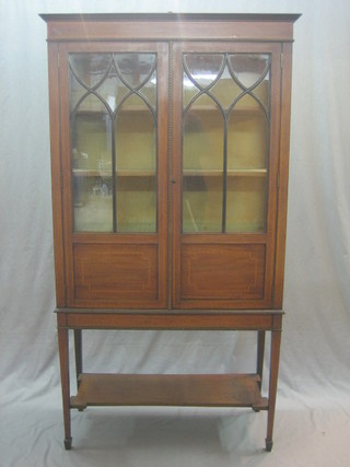 An Edwardian inlaid mahogany display cabinet with raised back, the interior fitted shelves enclosed by astragal glazed doors, raised on square tapering supports with undertier 36"