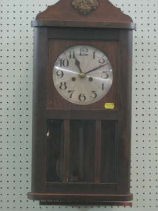 A striking wall clock with silvered dial contained in an oak case