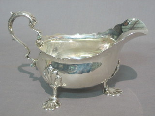An Edwardian Georgian style silver sauce boat with wavy cut border and C scroll handle, raised on 3 panel supports, Chester 1907 10 ozs