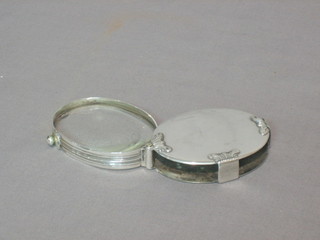 A 19th Century oval folding pocket magnifying glass contained in a silver plated mount (chips to lens)