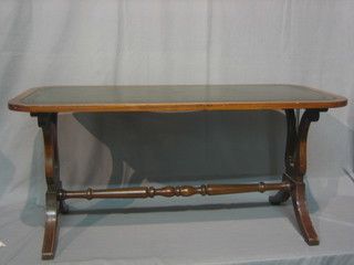 An oval Georgian style mahogany coffee table with inset tooled leather writing surface, raised on lyre end supports 36"