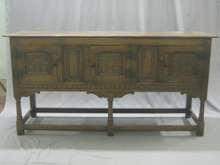 A carved oak dresser base enclosed by 3 panelled doors, raised on turned and block supports 66"
