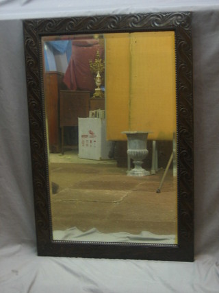 A rectangular bevelled plate mirror contained in a carved oak frame 36"