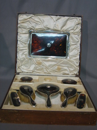 An 8 piece silver and tortoiseshell dressing table set comprising rectangular dressing table tray, a pair of cut glass powder bowls with lids, a pair of clothes brushes, a pair of hair brushes and a hand mirror, boxed, London 1926