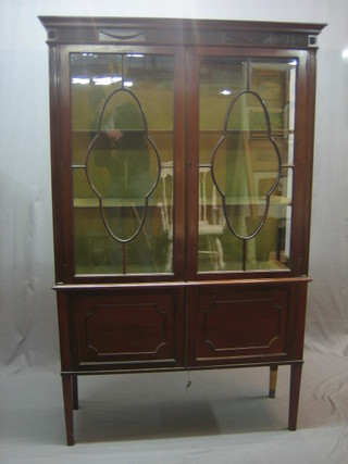 An Edwardian mahogany display cabinet, the interior fitted adjustable shelves enclosed by astragal glazed doors, the base fitted a double cupboard enclosed by panelled doors, raised on square feet 43"