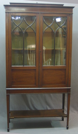 An  Edwardian inlaid mahogany display cabinet, the interior fitted adjustable shelves enclosed by an astragal glazed door with undertier, raised on square tapering supports ending in spade feet 36"