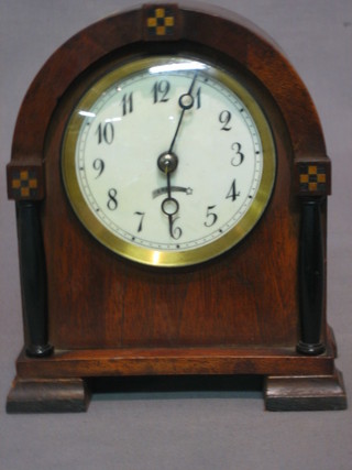 A bedroom timepiece with enamelled dial and Arabic numerals contained in an inlaid arch shaped case
