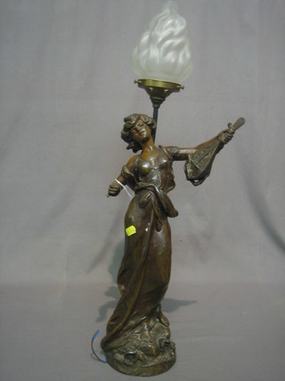 An Art Nouveau French spelter table lamp in the form of standing lady with mandolin complete with glass flame and shade, raised on a wooden base 28", signed, (f and r)