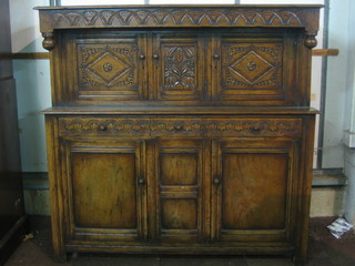 A carved oak court cupboard, the upper section fitted triple cupboard, the base fitted 1 long and 2 short drawers above a triple cupboard, raised on square supports 60"