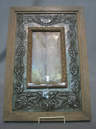 An Art Nouveau embossed copper mirror or photograph frame contained in an oak frame 18" x 20"